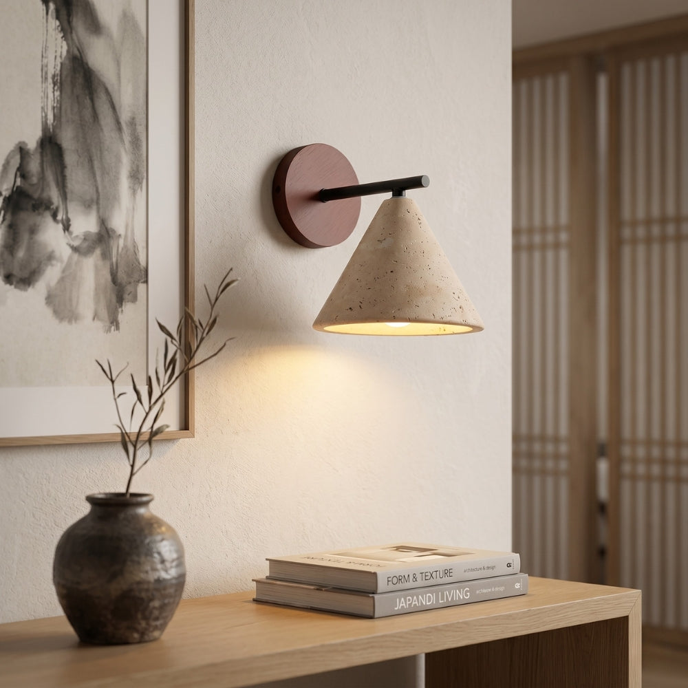 Modern wall lamp on a wooden table with books and a vase in a room setting.