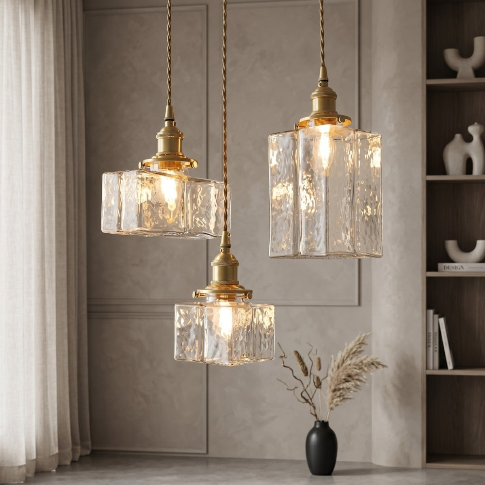 Three pendant lights with glass shades hanging in a room with a neutral color scheme.