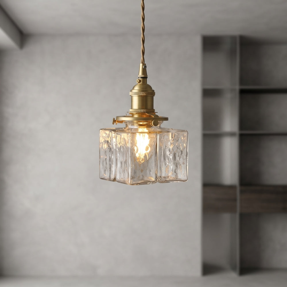 Vintage-style pendant light with glass shade and brass fixture in a minimalistic room.
