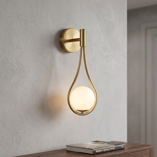 Gold wall sconce with a round bulb on a neutral wall