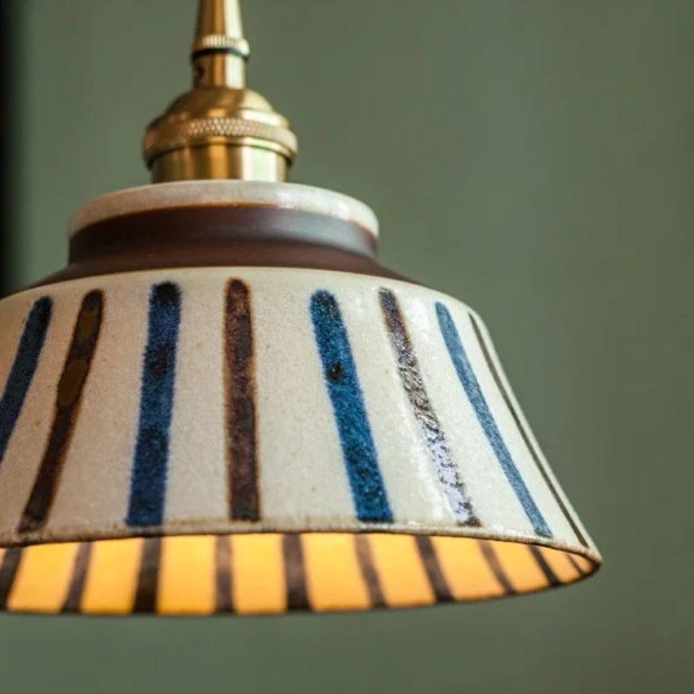 Striped lampshade with a gold fixture on a green background