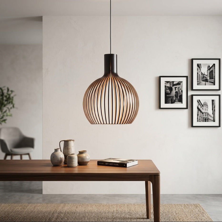 Modern pendant light hanging above a wooden table with decorative items in a minimalistic room.