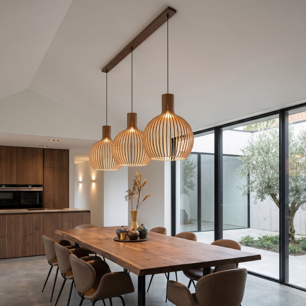 Modern dining area with wooden table and pendant lights in a well-lit room.