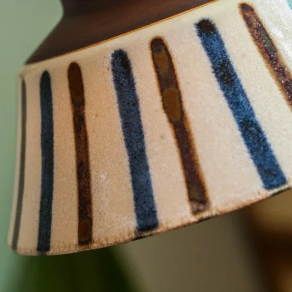 Close-up of a ceramic vase with striped pattern on a blurred background