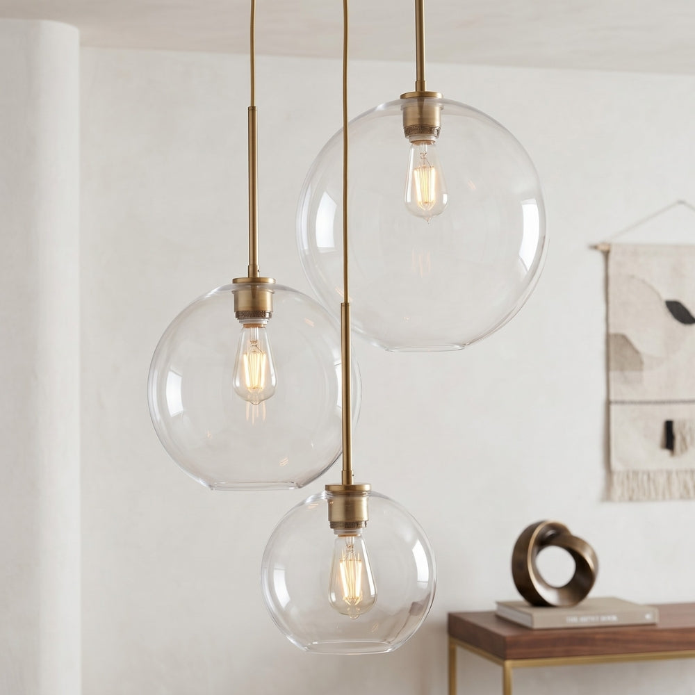 Three spherical glass pendant lights with brass fixtures hanging in a room.