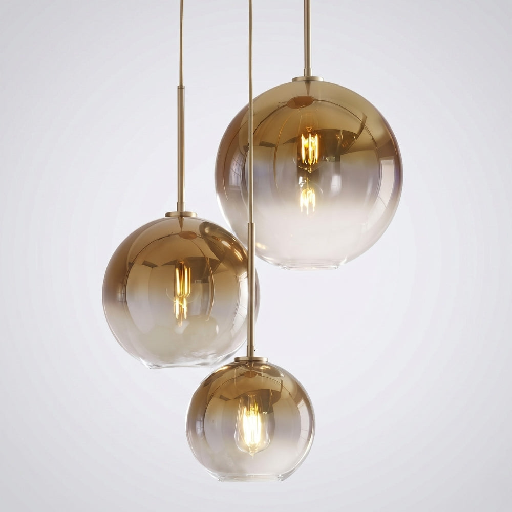 Three gold pendant lights with glass shades on a white background