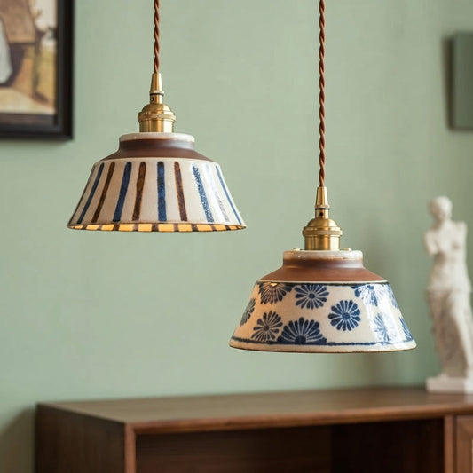 Two ceramic pendant lights with decorative patterns hanging against a green wall.