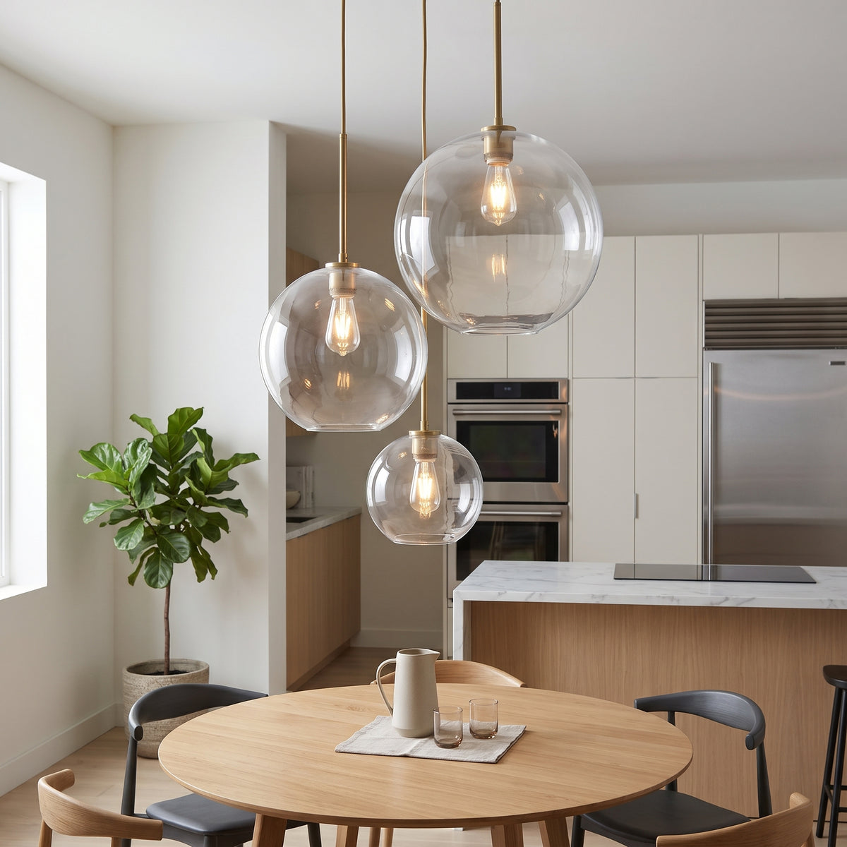 Three clear glass globe pendant lights with warm Edison bulbs hanging over a round wooden dining table in a bright, modern kitchen and dining room.