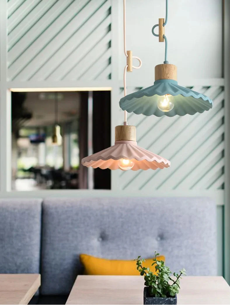 Two pendant lights hanging above a table with a plant in a restaurant setting.