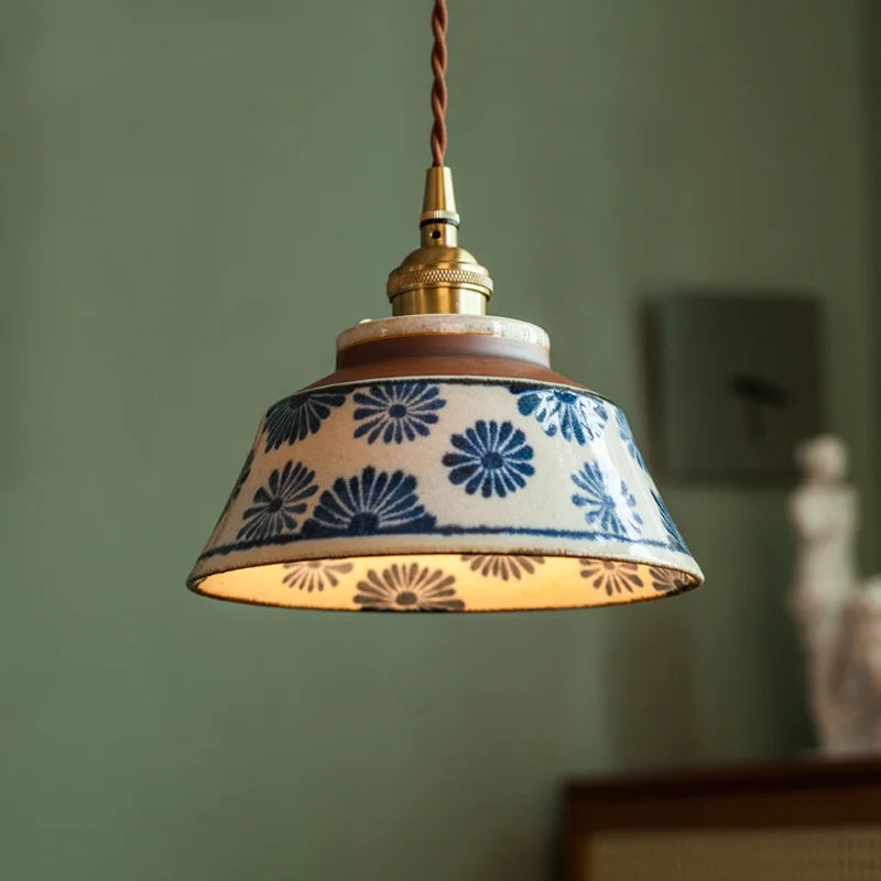 Pendant light with decorative ceramic shade against a green wall