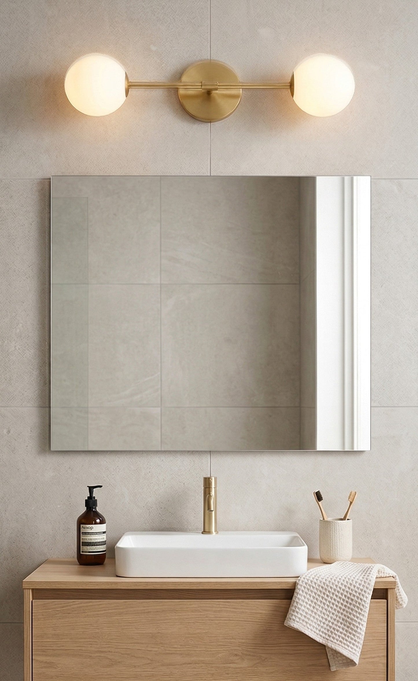 Bathroom setup with a mirror, light fixture, sink, and toiletries.