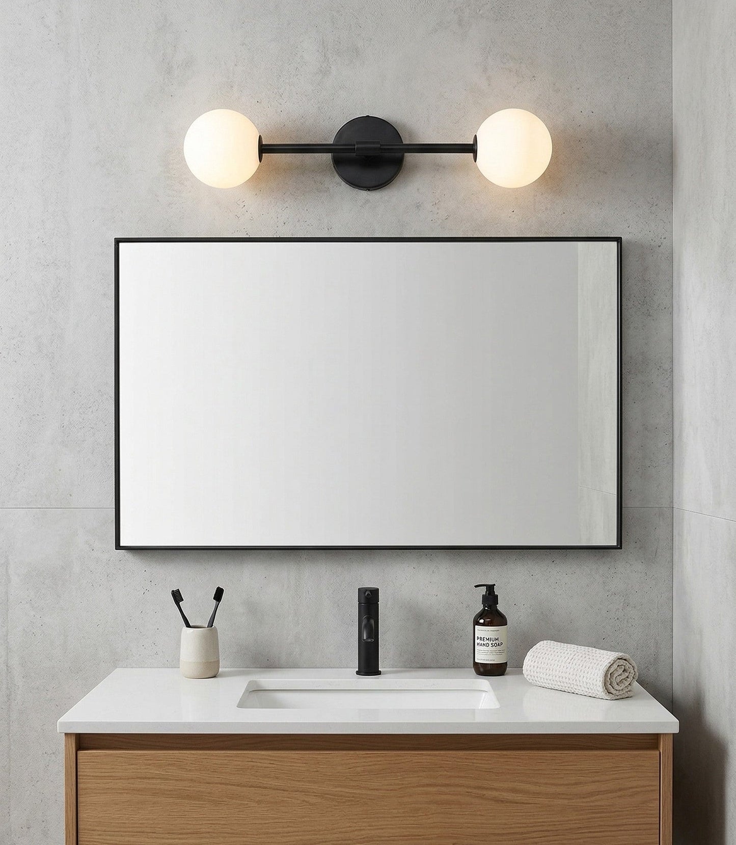 Bathroom vanity with mirror, light fixture, and toiletries against a gray wall.