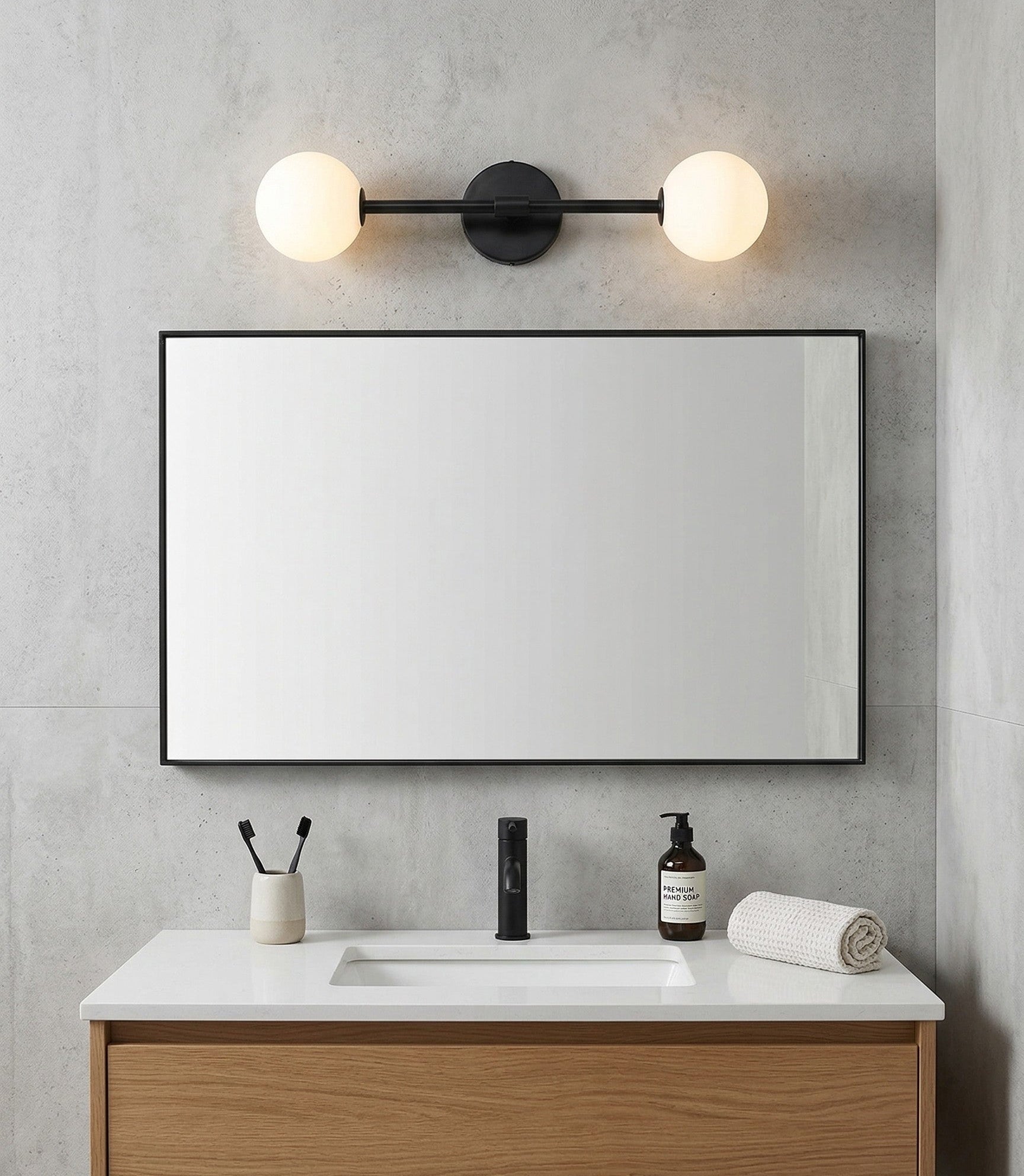 Bathroom vanity with mirror, light fixture, and toiletries against a gray wall.