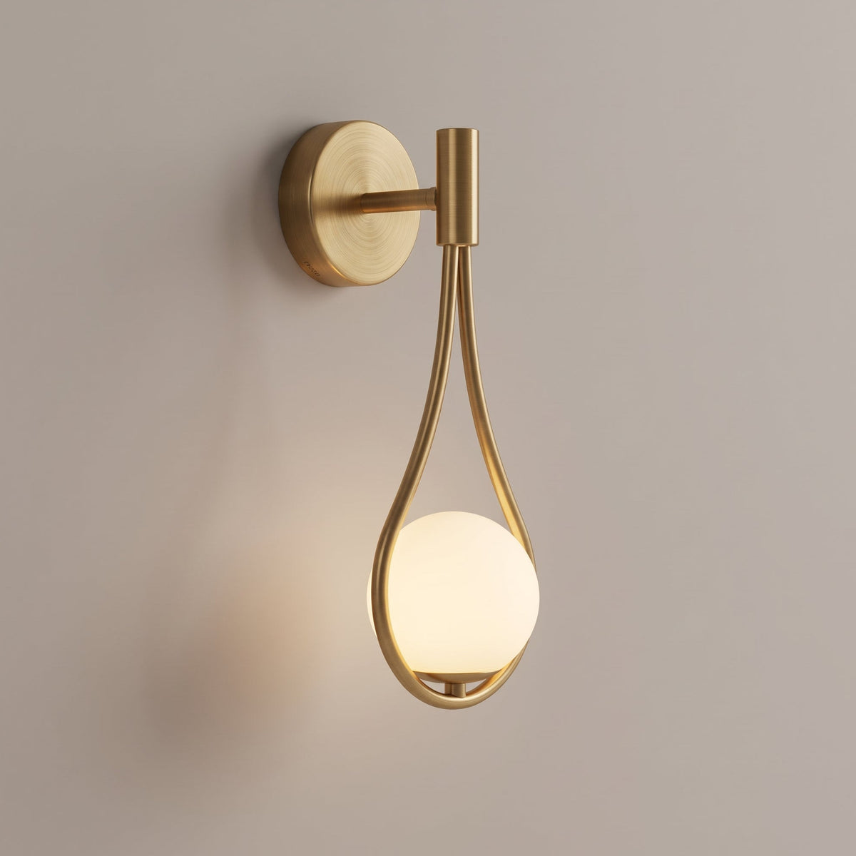A modern wall sconce with a brushed gold metal frame and a glowing frosted glass globe, mounted on a plain warm beige wall.